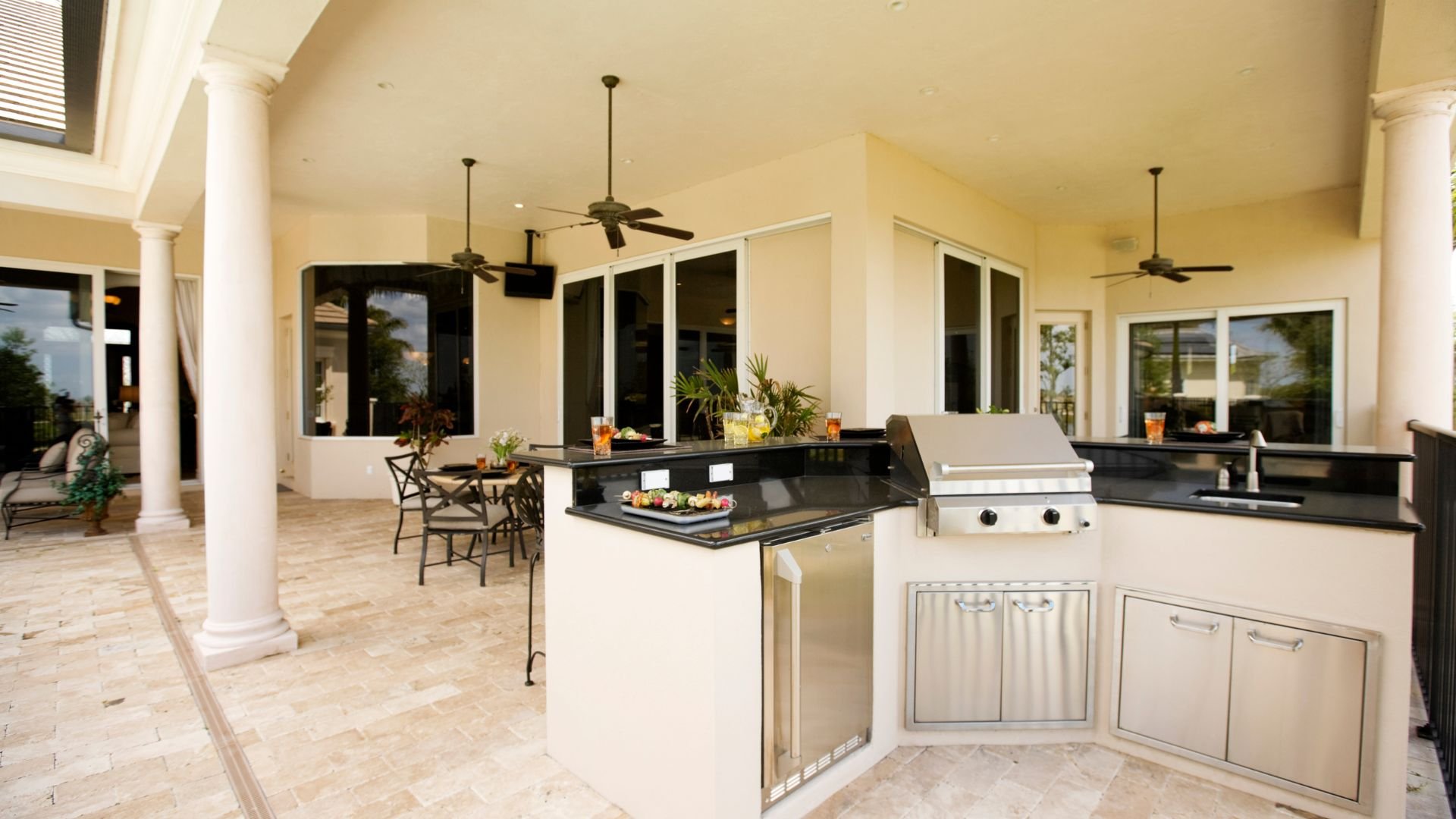 Luxurious outdoor kitchen with grill, marble countertops, and classic columns