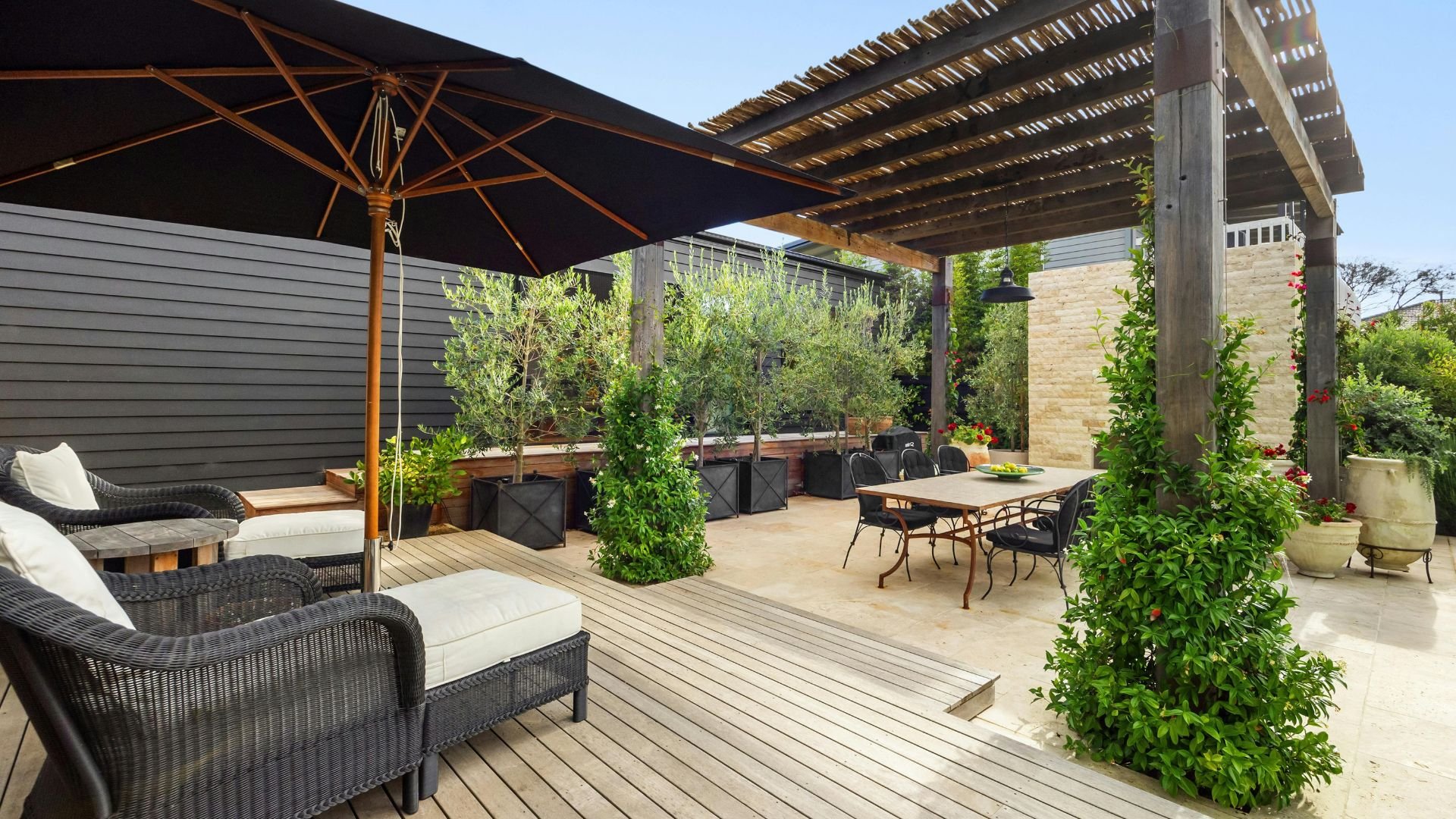 Luxurious outdoor patio with umbrella, seating, plants, and dining area