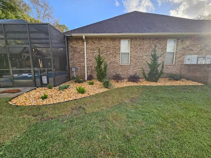 Brick house with landscaped yard, mulch beds, and screen enclosure